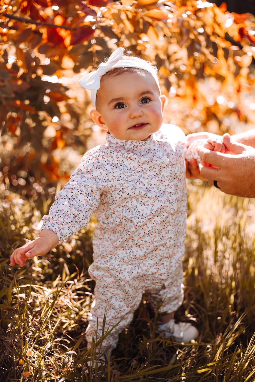 A baby taking supported steps outdoors