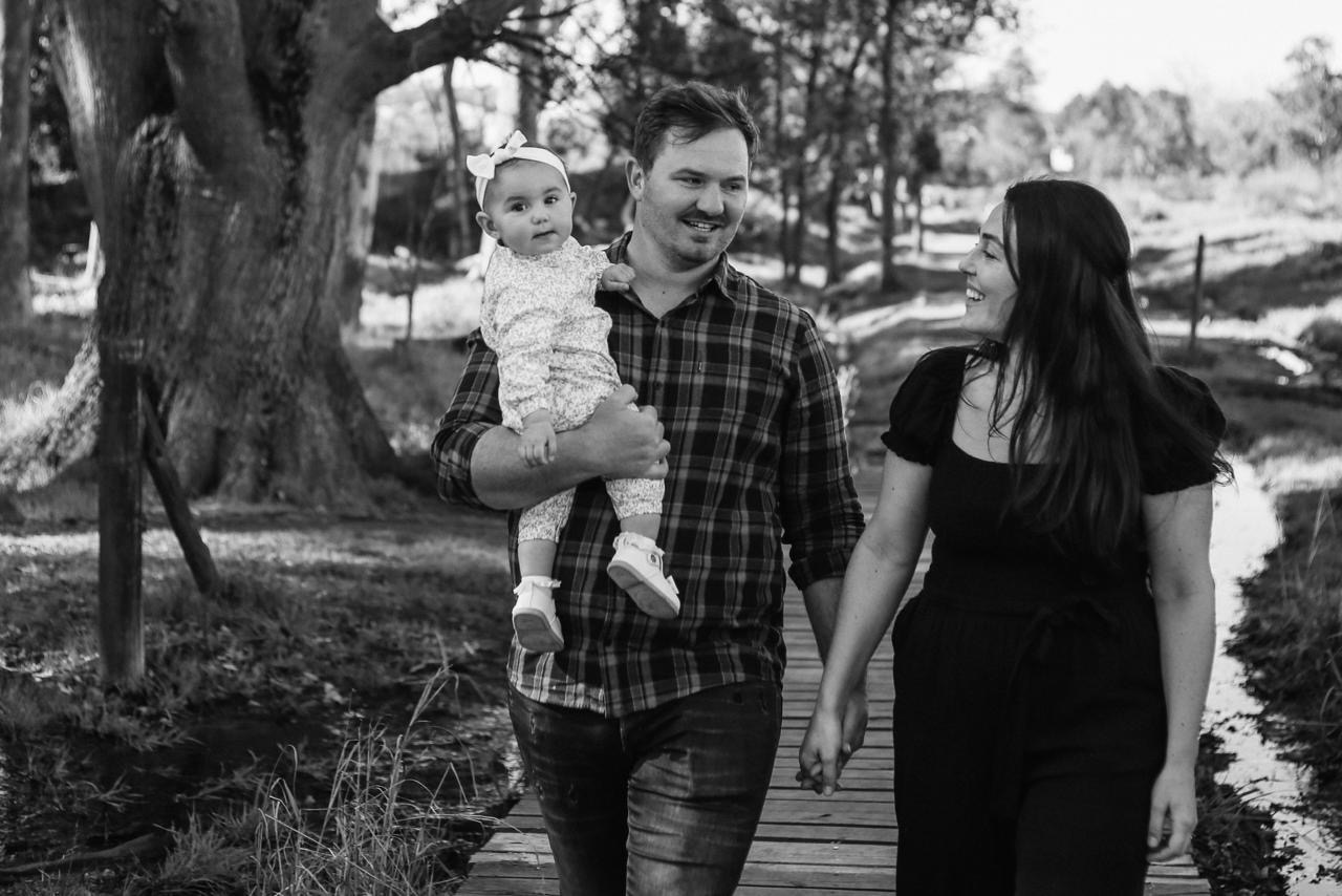 A mother and father walking outdoors with their baby