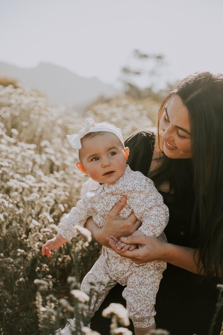 A mother holding her baby among wildflowers
